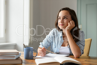 Student teenage girl studying at home daydreaming