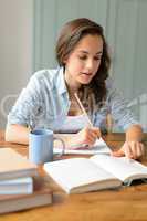 Teenage student girl studying book at home