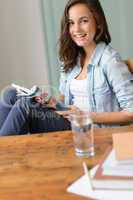 Smiling teenage girl reading magazine at home
