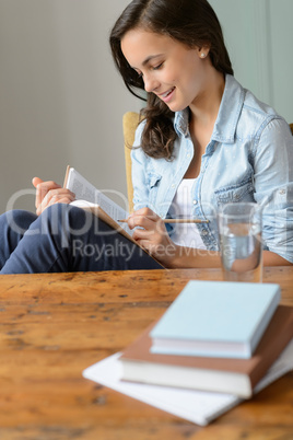 Teenage girl student reading book at home