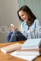 Cheerful teenage girl looking mobile phone home