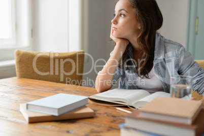 Bored student girl sitting home looking away