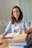 Cheerful teenage girl studying at home