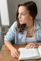 Thoughtful teenage girl book looking away home