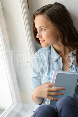 Beautiful teenage girl looking out the window