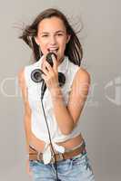 Beautiful teenage girl singing with microphone