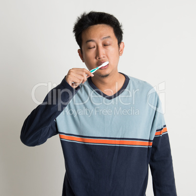 Asian male brushing teeth