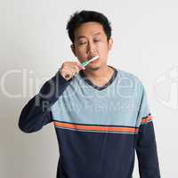 Asian male brushing teeth