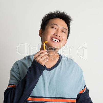 Asian male shaving his beard