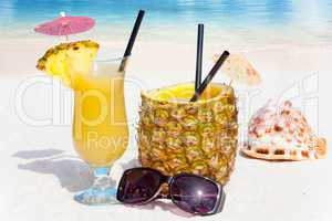 Ananasfrucht und Saft am Strand