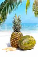 Tropische Früchte am Sandstrand unter Palmen