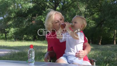 Grandmother with her grandson in the park, child drinking juice