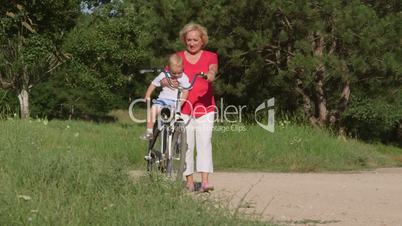 Smiling senior woman with grandson enjoying time together on bicycle