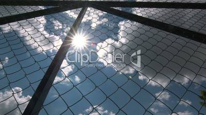 Dolly: Sun shining through the chain link iron wire fencing