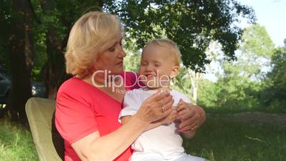 Attractive grandmother with her grandchild having fun in summer park