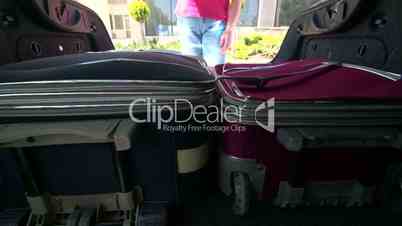 Woman packing her luggage into car trunk inside view