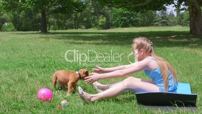 Little girl with a puppy dog having fun on grass in summer park