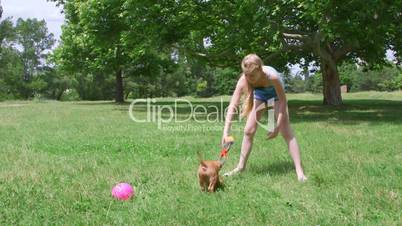 Child playing with her funny puppy dog on grass