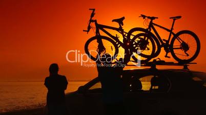 Summer travelers near his car with mounted bikes on beach vacation
