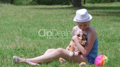 Child holding puppy dog on a grass