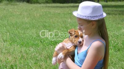 Little girl holding puppy on a grass
