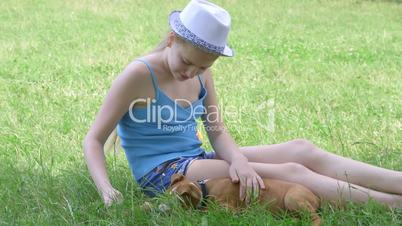 Child with her puppy dog sitting,on a green lawn
