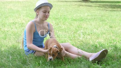 Child with puppy dog on green lawn in summer day