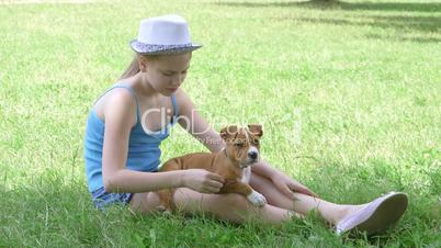 Little girl with puppy on green lawn in summer day