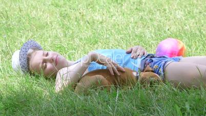 Child with puppy dog relaxing on the grass in summer day