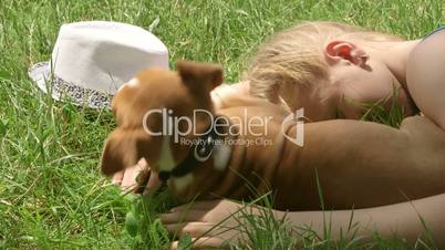 Child with puppy dreaming on grass in summer day