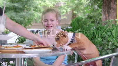 Child and puppy eating pizza in fast food restaurant outdoors