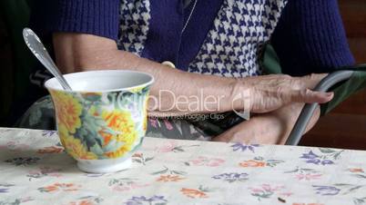 Elderly woman at the table with a cup of drink