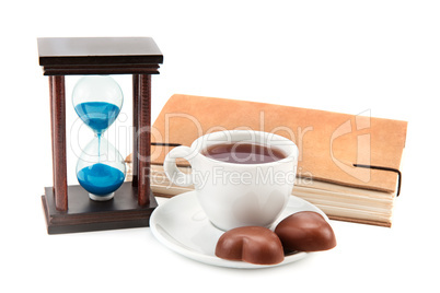 hourglass tea cup and a book on a white background