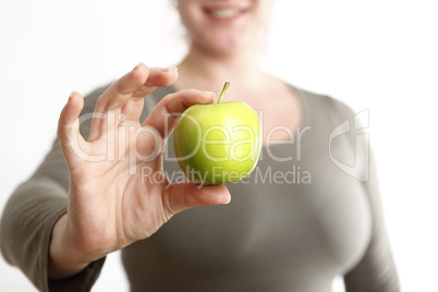 Woman holds a green apple into to camera