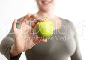 Woman holds a green apple into to camera