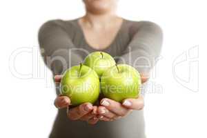 Woman holds three green apples into to camera