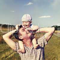 father holds a small child on his shoulders