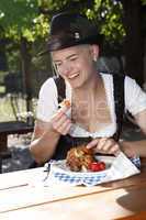 Blonde girl eats half chicken in a traditional beer garden