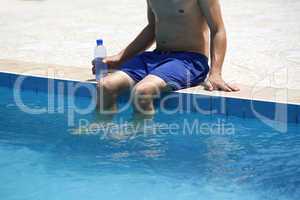 Attractive man with blue swimsuit and a bottle of water enjoys s