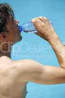 Attractive man drinks water at the swimming pool