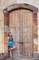 young woman in long dress standing in front an old door.  Focus