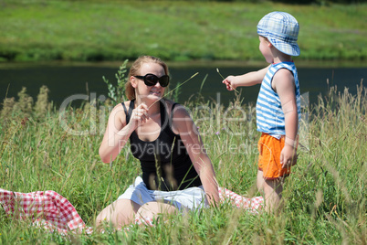 Mother and son playing with grass on the meadow