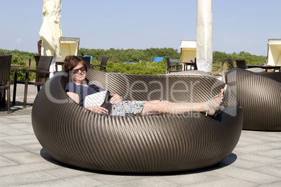 Woman lying in wicker furniture