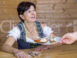 Woman in Bavarian dress gets white sausages served