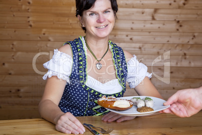 Woman in Bavarian dress gets white sausages served