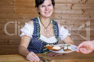 Woman in Bavarian dress gets white sausages served