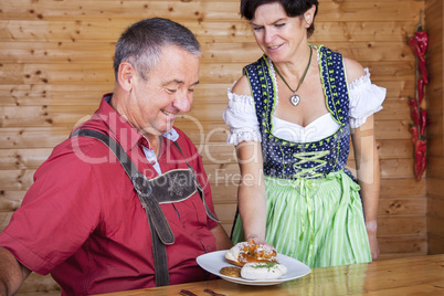 Woman in traditional Bavarian Tracht serves one white sausages