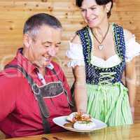 Woman in traditional Bavarian Tracht serves one white sausages
