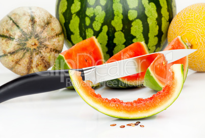 Messer steckt in Melone vor verschiedenen Melonen