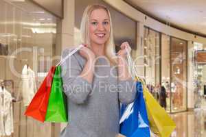 Blonde Frau beim Einkaufen mit Einkaufstaschen im Einkaufszentru